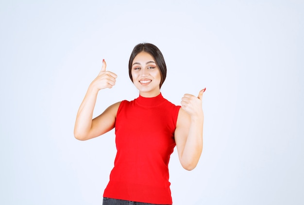 Girl in red shirt showing enjoyment hand sign.