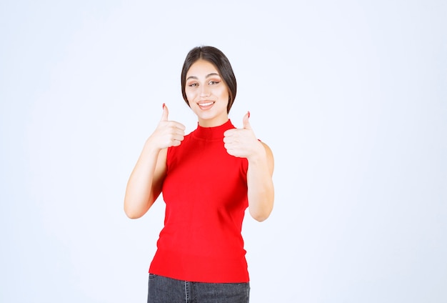 Girl in red shirt showing enjoyment hand sign.