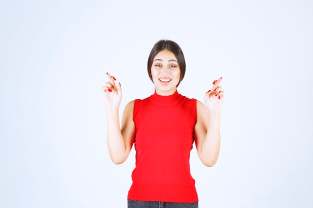 Девушка в красной рубашке показывая знак креста пальца.