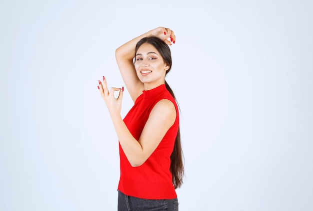 Girl in red shirt showing positive hand sign.