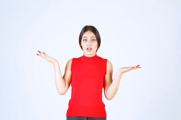 Girl in red shirt showing something in her open hand.