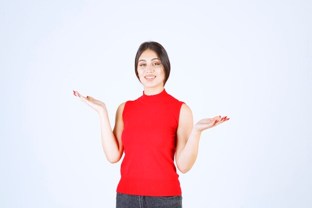 Girl in red shirt showing something in her open hand.