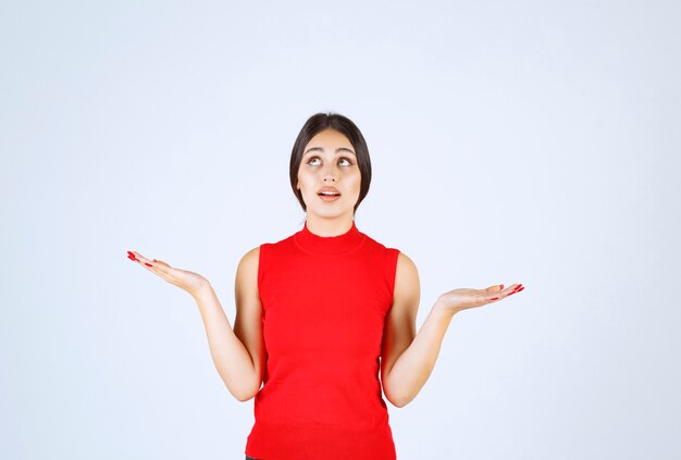 Girl in red shirt showing something in her open hand.