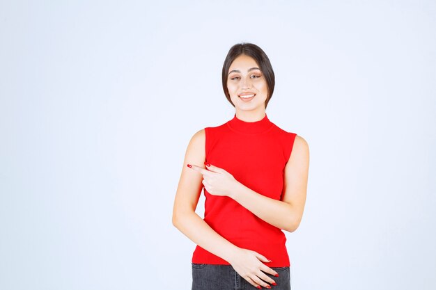 Girl in red shirt showing something on the left.