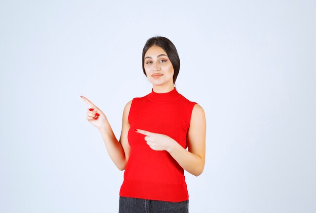 Girl in red shirt showing something on the left.