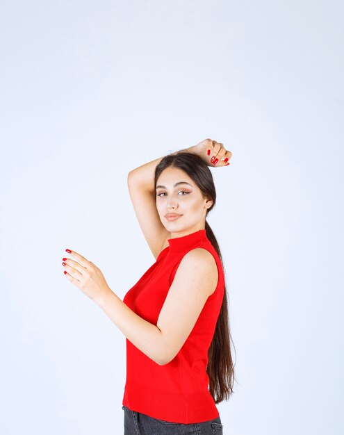 Girl in red shirt showing something on the left.