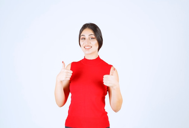 Girl in red shirt showing thumbs up.