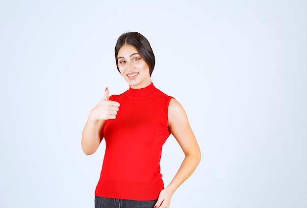 Girl in red shirt showing thumbs up.