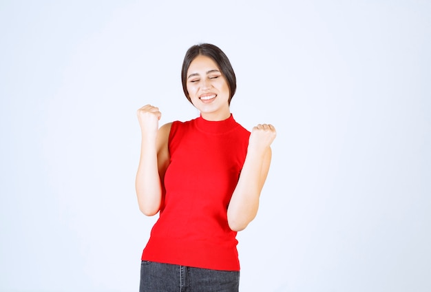 Girl in red showing her fists and feels successful.