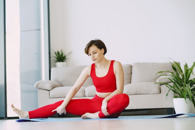 Girl in a red sports uniform practising yoga at home