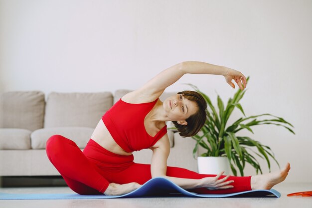 Девушка в красной спортивной форме практикующих йогу дома