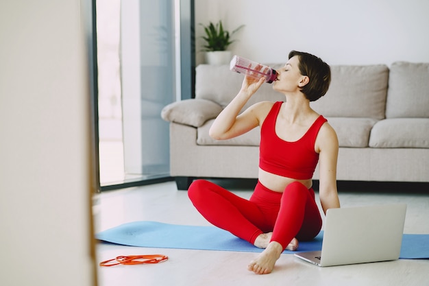 Девушка в красной спортивной форме практикующих йогу дома