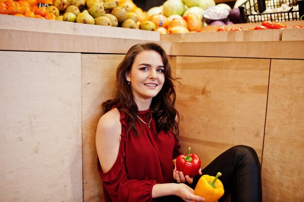 Girl in red throw peppers on fruits store