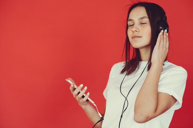 Girl on a red wall with headphones