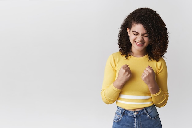 Girl rejoicing cheering achieving prize close eyes yelling yes clench fists joyfully celebrate triumph victory standing happily enjoying sweet taste success hear good news achieve goal got job