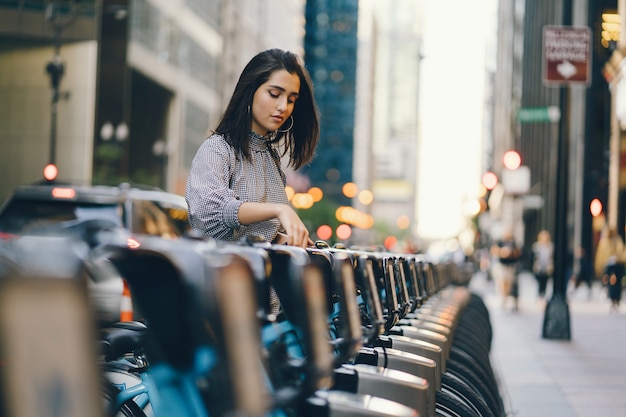 자전거 스탠드에서 도시 자전거를 임대하는 여자
