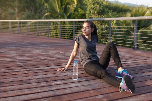 Foto gratuita ragazza che riposa accanto a una bottiglia d'acqua