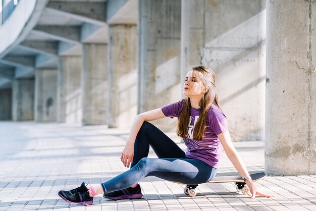 Девушка, сидящая на скейтборде