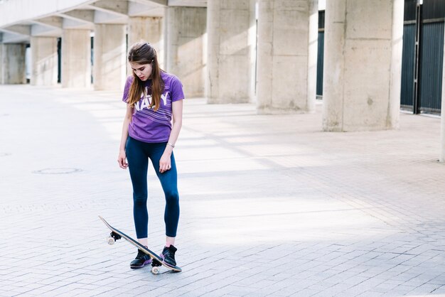 소녀는 그녀의 발을 그녀의 스케이트 보드에 달려있다
