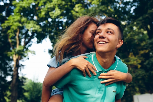 Foto gratuita ragazza a cavallo su bel ragazzo sorridente all'aperto