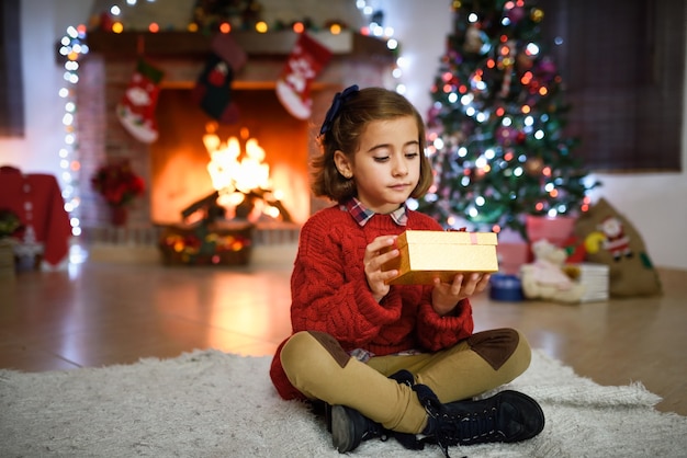 Girl in a room decorated for christmas with golden gift box