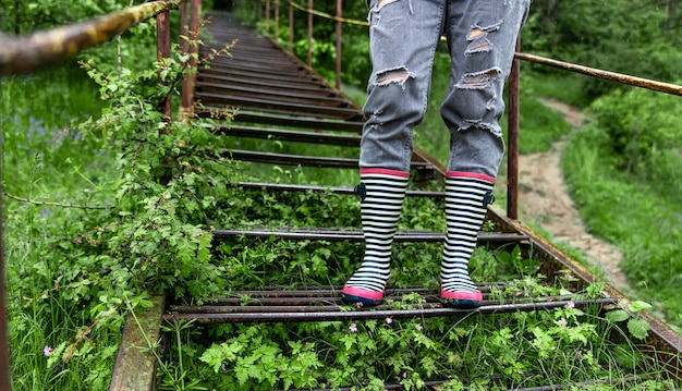 A girl in rubber boots walks in the forest in rainy spring weather close up.