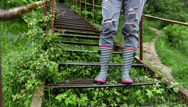 春の雨天のクローズ アップで、ゴム長靴の女の子が森を歩きます。