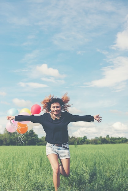 Foto gratuita ragazza che funziona con palloncini colores nel campo