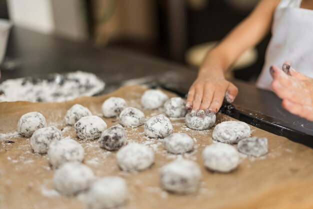 Girl's hand applying flour on raw cookies