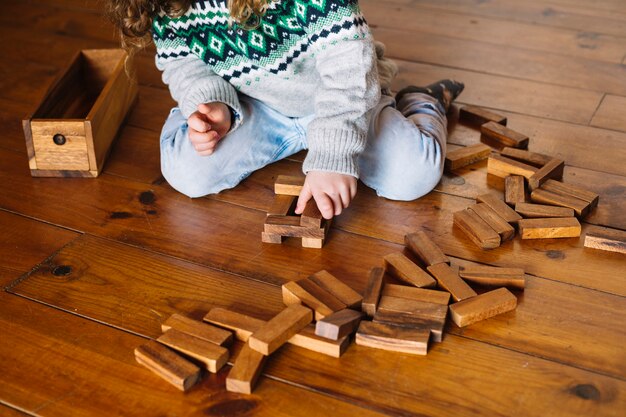 Girl's hand playing wooden block game at home