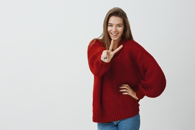 冒険へようこそ。トレンディなルーズな赤いセーターを着た魅力的なヨーロッパの女性の屋内ショット
