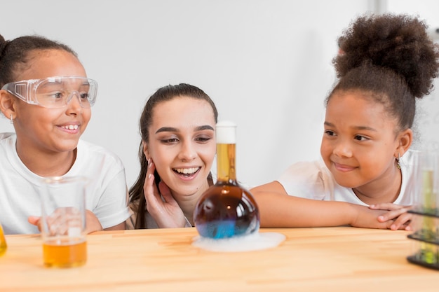 Girl scientists and woman watching a chemistry experiment