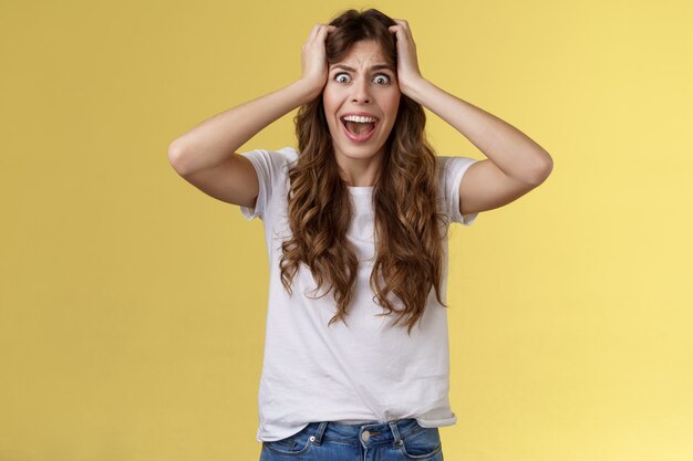 Girl screaming panic. Troubled distressed anxious woman see huge mess terrified feel sorrow shouting shocked grab head hopeless problem terrible situation yelling shook stunned yellow background.