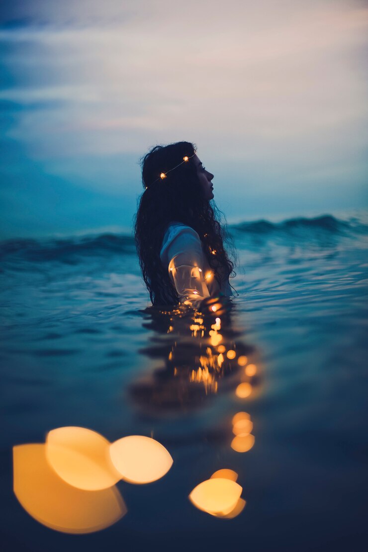 Free Photo girl in the sea in the dusk time with lights around