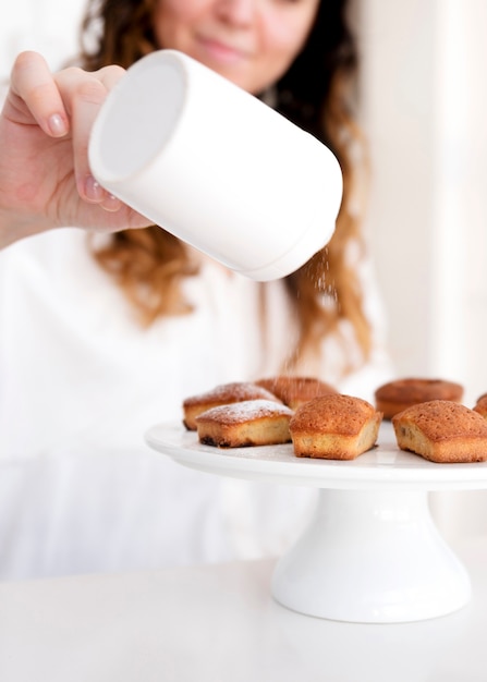 Girl serving icing sugar on muffin top