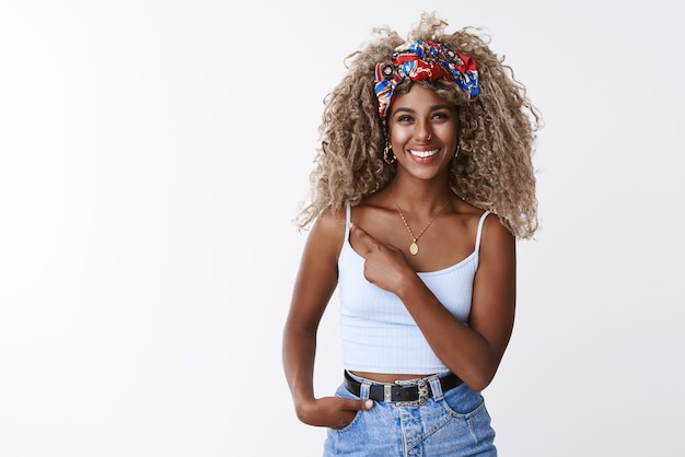 Girl sharing cool link suggest place to hang out Attractive friendly curlyhaired blond hipster woman with piercing smiling carefree as pointing finger left at blank copy space white background