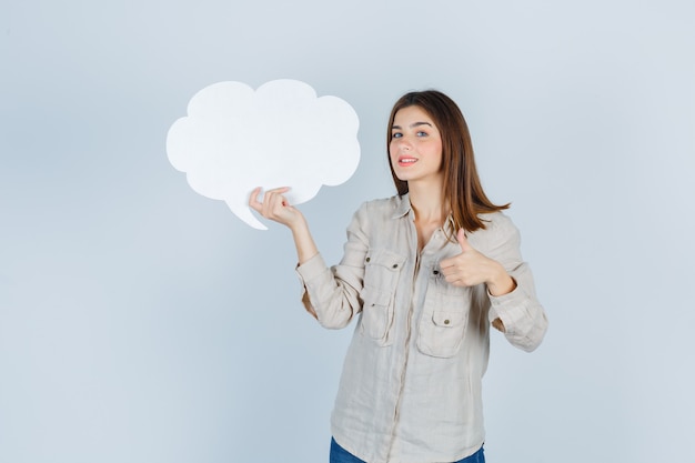 girl in shirt holding speech bubble, showing thumb up and looking jovial 