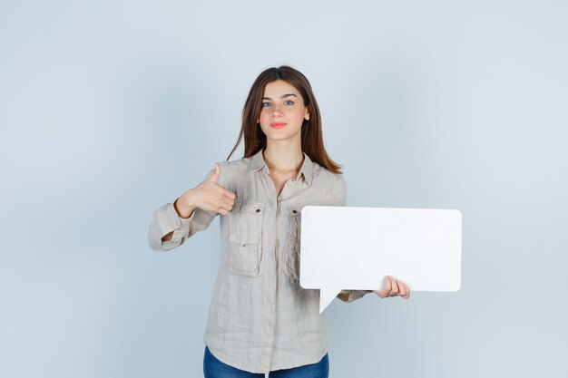 girl in shirt holding speech bubble, showing thumb up and looking pleased 