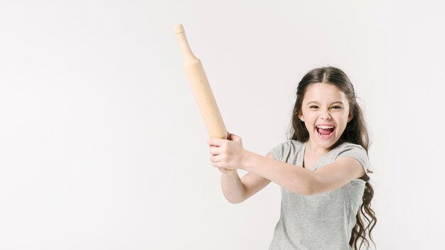 Girl shouting with rolling-pin in studio