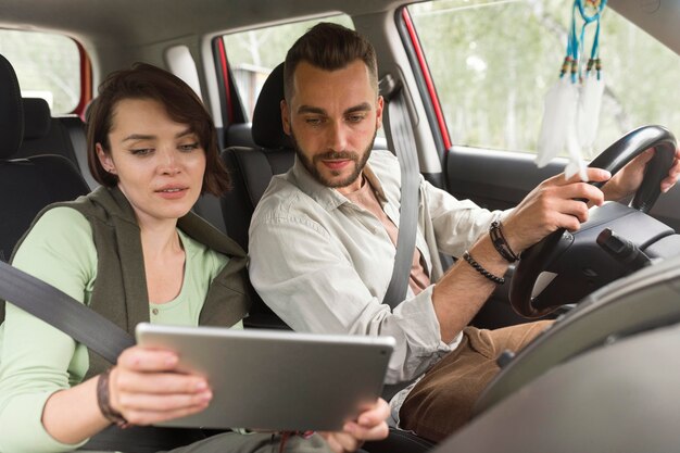 Girl showing boyfriend tablet in car