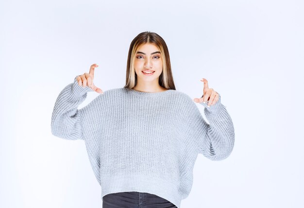 Girl showing the dimensions of an object.