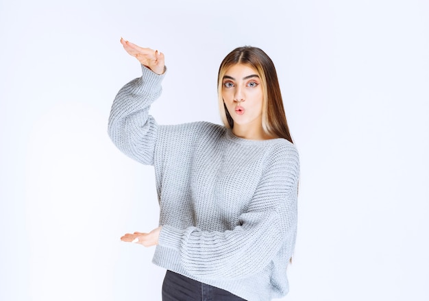 Girl showing the dimensions of an object.