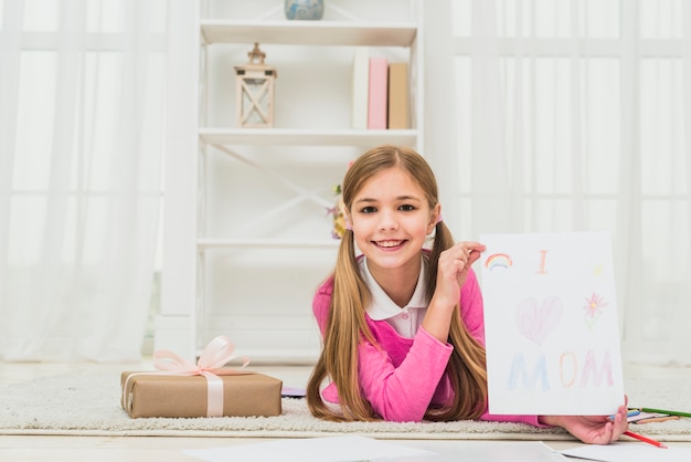 Girl showing drawing with I love mom inscription 