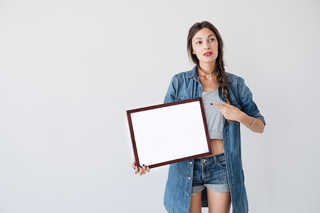 Girl showing to an empty blank white placard or poster