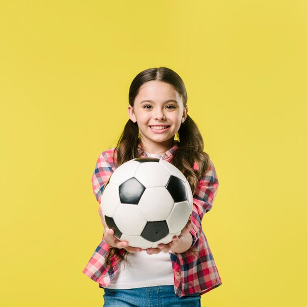 Girl showing football in studio
