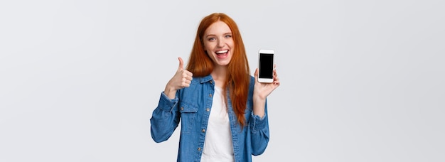 Free photo girl showing friend cool new mobile game attractive cheerful redhead woman holding smartphone introd