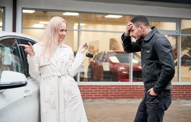 Girl showing guy keys to newly purchased automobile