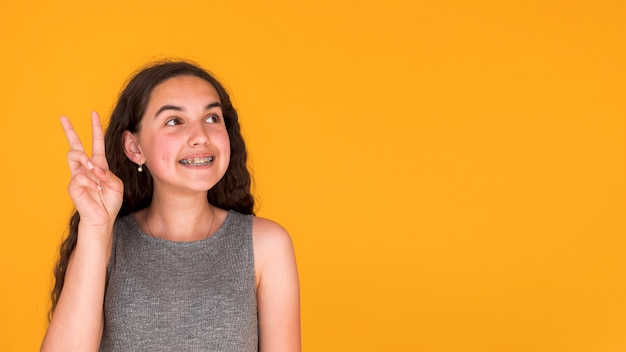 Ragazza che mostra il segno di pace mentre distogliendo lo sguardo