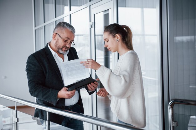 Girl showing results of work to her boss in eyewears and grey beard