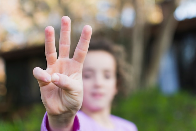 Foto gratuita una ragazza che mostra gesto di mano di tre dita di saluto